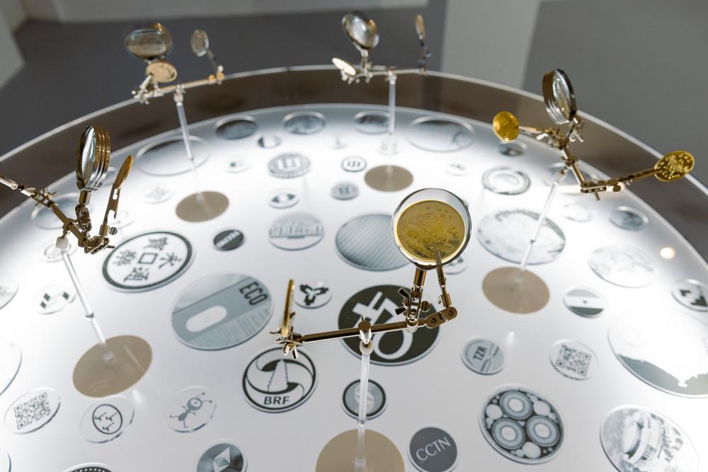 Musquiqui Chihying, The Culture Center, 2018 –2020, installation, light table, magnifying glass, zinc alloy coins, 100 × 120 cm, photo: Angelika Zinzow, © basis e.V.